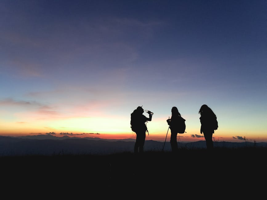 Group of hikers silhouetted against a vibrant sunset, enjoying an adventurous outdoor trek